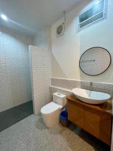 een badkamer met een toilet, een wastafel en een spiegel bij Sunny Cove Beach Resort Koh Phayam in Ranong