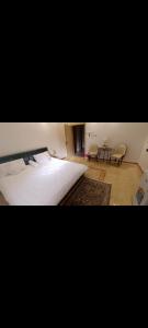 a bedroom with a large white bed and a table at الينبوع الأخضر in Al Madinah