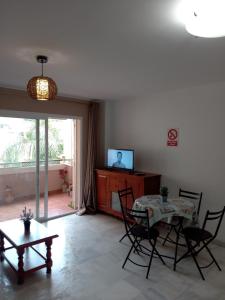 a living room with a table and chairs and a television at Apartamento Mirasol con parking privado in Fuengirola