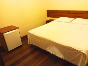 1 dormitorio con cama blanca y mesita de noche en Quarto De Casal Econômico en Ouro Preto