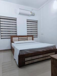 a bed in a white room with two windows at Munroe La Casa in Kollam