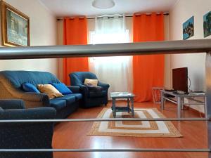 a living room with a blue couch and orange curtains at Quinta das rãs in Ponta Delgada