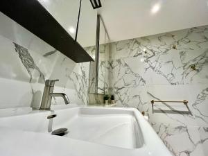 a white sink in a bathroom with a marble wall at Aquarius at St. George Wharf in London