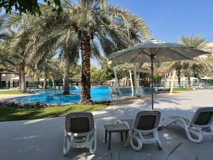 um grupo de cadeiras e um guarda-sol junto a uma piscina em Entire apartment in Remraam community em Dubai