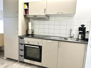 una cocina con armarios blancos y fregadero en Ferienwohnung De Priel en Dorum