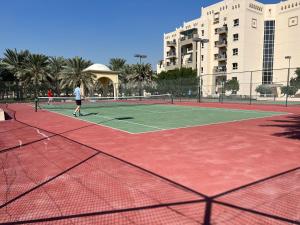uma pessoa está a jogar ténis num campo de ténis em Entire apartment in Remraam community em Dubai
