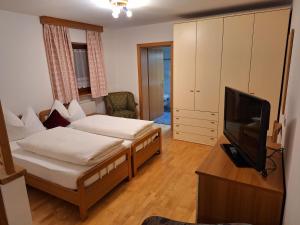 a hotel room with two beds and a television at Apartments Insam in Santa Cristina Gherdëina