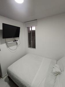 um quarto com uma cama e uma televisão de ecrã plano em Apartahotel Barú - Usaquén em Bogotá