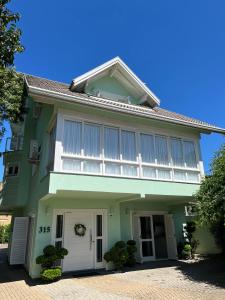 a green house with white shutters on it at San Clemente Residence in Gramado