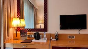 a hotel room with a desk with a tv on the wall at Dubai Grand Hotel by Fortune, Dubai Airport in Dubai