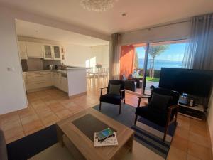 Mini villa Hameaux des Sanguinaires AJACCIO في أجاكسيو: غرفة معيشة مع طاولة ومطبخ مع اطلالة