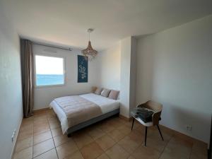 Mini villa Hameaux des Sanguinaires AJACCIO في أجاكسيو: غرفة نوم بها سرير ونافذة وكرسي +17 صورة