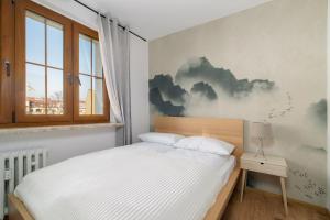 een slaapkamer met een bed en een schilderij van wolken aan de muur bij Comfortable Two-Bedroom Apartment Poznań by Renters in Poznań