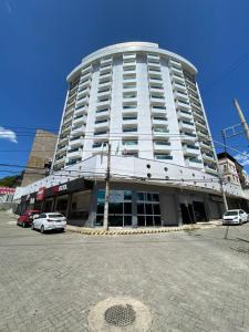 a large white building with cars parked in front of it at San Diego Governador Valadares in Governador Valadares