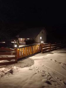 Una valla y una casa en la nieve por la noche en Dom Pod Gaikiem, en Łękawica