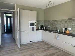 a kitchen with white cabinets and a wooden floor at Weidezicht in Cromvoirt
