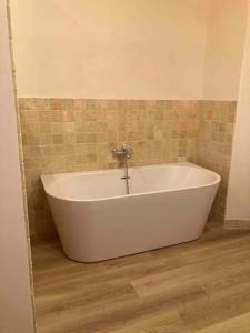 een badkamer met een wit bad en een houten vloer bij La Maison Grise - vacances familiales in Le Tholy