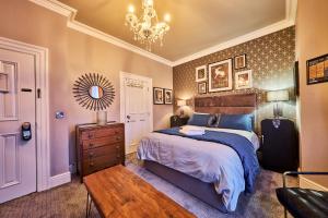 ein Schlafzimmer mit einem Bett, einer Kommode und einem Kronleuchter in der Unterkunft Art House in Derry Londonderry
