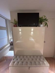 a white couch in a living room with a flat screen tv at Renovated Parkside Gem - 2 person studio in the Pijp in Amsterdam
