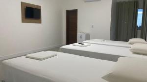 two white beds in a room with a television at Terra das Palmeiras in Barreirinhas +4 photos