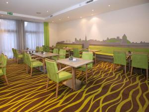 a restaurant with tables and chairs on a carpet at Hotel Am Gorzberg Greifswald in Greifswald