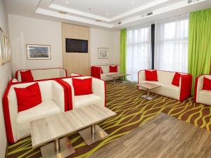 a living room with two white couches and red pillows at Hotel Am Gorzberg Greifswald in Greifswald