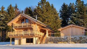 a large log cabin with a balcony and a stone wall at Böhmerwald Lodges in Ulrichsberg