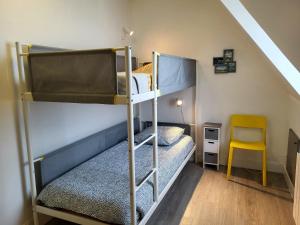 een slaapkamer met 2 stapelbedden en een gele stoel bij L'Hermitage, villa front de mer in Pirou