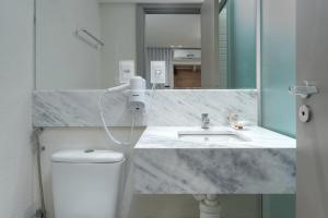 uma casa de banho com um lavatório, um WC e um espelho. em Vistamar Hotel em Maceió