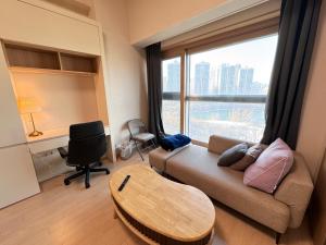 Una sala de estar con un sofá y una mesa y una ventana. en LAKE VIEW LOFT JAMSIL, en Seúl