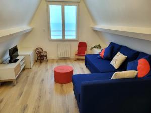 een woonkamer met een blauwe bank en een raam bij L'Hermitage, villa front de mer in Pirou