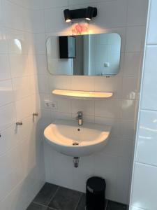 een witte badkamer met een wastafel en een spiegel bij Weidezicht in Cromvoirt