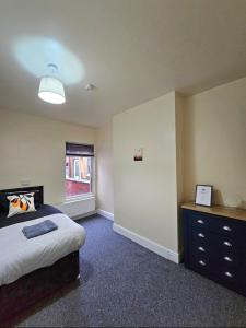 a bedroom with a bed and a dresser and a window at spacious luxury near city center free parking in Coventry