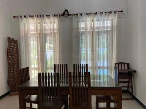 une salle à manger avec une table, des chaises et des fenêtres dans l'établissement Lady Nelly villa Hikkaduwa, à Hikkaduwa 35 autres photos