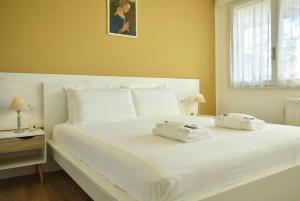 a white bed with two towels on top of it at Welc-ōM Shabby Montegrotto in Padova