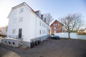 ein weißes Haus mit einem Auto daneben geparkt in der Unterkunft aday - 3 bedroom - Modern Living Apartment - Aalborg Center in Aalborg