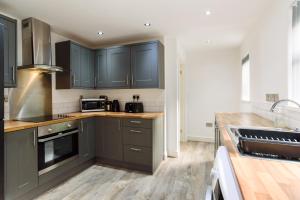 a kitchen with dark blue cabinets and wooden floors at Caerau Gardens in Newport
