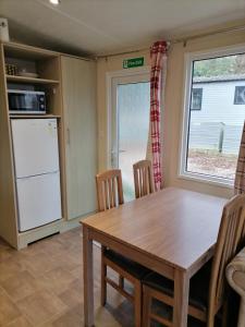 cocina con mesa, sillas y nevera en Beauport Holiday Park en Hastings