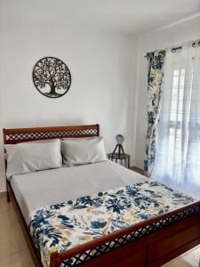 a bed in a bedroom with a tree picture on the wall at Sea La Vie Villa in Grande Gaube