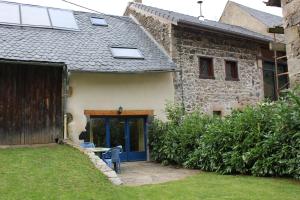 una casa de piedra con una puerta azul y un patio en Au coeur des Volcans d'Auvergne, en Ceyssat