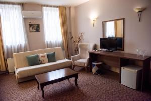 a hotel room with a couch and a desk and a mirror at Hotel Monte Cristo in Blagoevgrad
