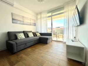 uma sala de estar com um sofá e uma varanda em Costa Daurada Apartaments - AQUARIO PINEDA em La Pineda