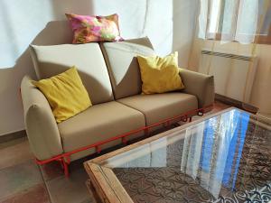 d'un canapé avec des oreillers jaunes et une table en verre. dans l'établissement Petit cocon à Mourepiane, à Marseille
