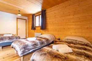 three beds in a room with wooden walls at Le petit Paradis, chalet au coeur des 3 vallées in Saint-Marcel