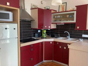 a kitchen with red cabinets and a white refrigerator at Royan - APPARTEMENT au coeur du CENTRE-VILLE - PLAGE à 200m SEULEMENT in Royan