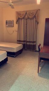 - une chambre avec deux lits, une chaise et une fenêtre dans l'établissement نزل الخالدية, à Al Qunfudhah