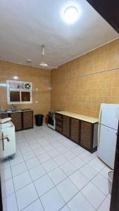 a large kitchen with white tiled floors and appliances at نزل الخالدية in Al Qunfudhah