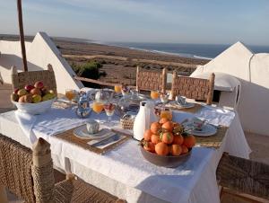 Riad Sahara Sunset Beach Agadir في Douaïra: طاولة مع وعاء من الفواكه على رأس طاولة
