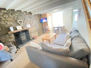 a living room with a couch and a stone wall at The Cwtch, Log Fire, Sleeps 5, Nr Zip World, Brecon and Bike Park Wales in Aberdare