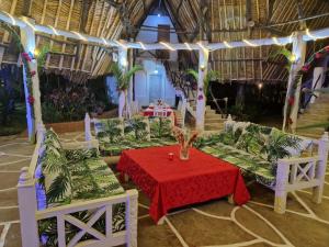 ein Zimmer mit einem Tisch und Stühlen mit einem roten Tischtuch in der Unterkunft Le Grand Forest dreams Resort in Ukunda